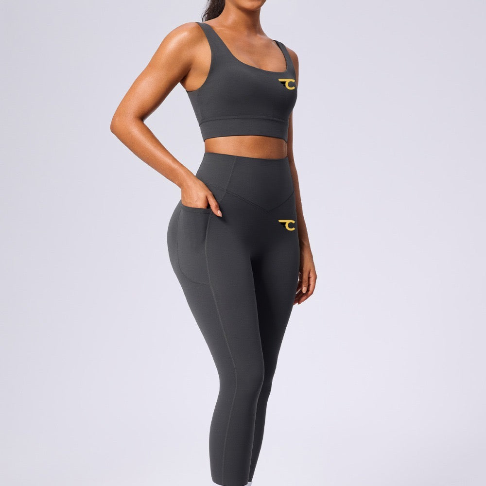 Person wearing a black sports bra and leggings set with a logo on a light gray background